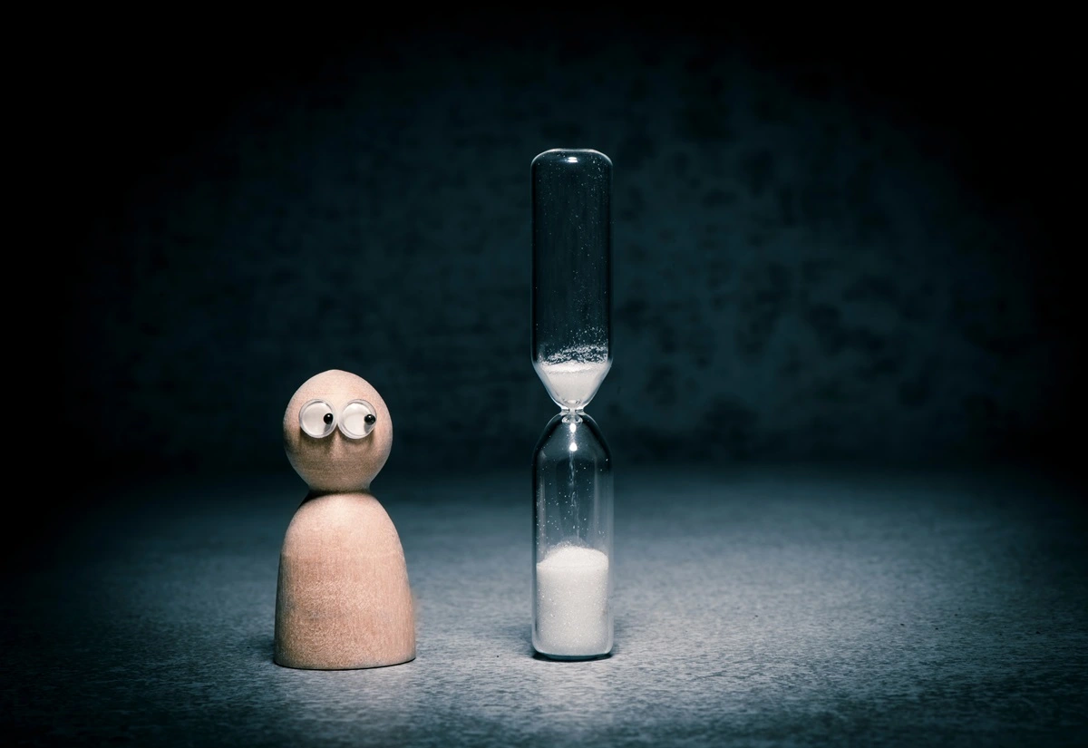 How Long Does SEO Take? Little Wooden Person Watching Hourglass