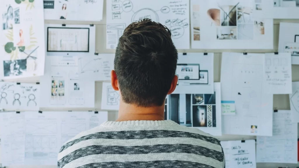 Man pondering in front of board with ideas for multivariant testing in marketing